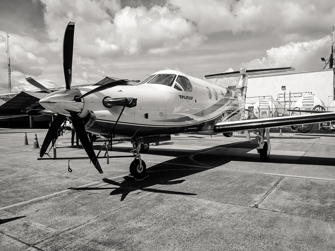 Black and white image of a modern aircraft at Bogotá airport under a cloudy sky.